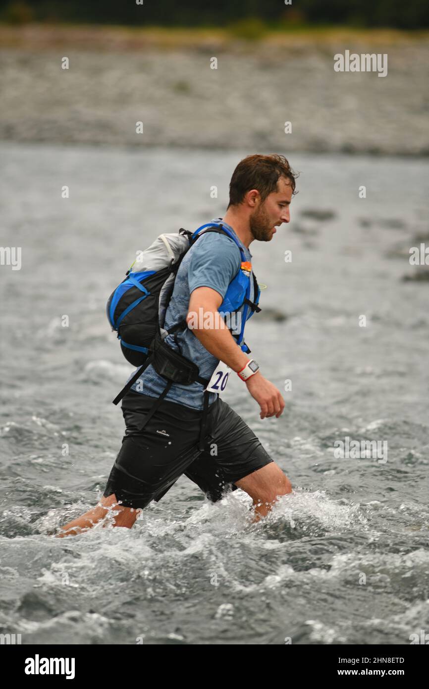 ARTHURS PASS, NUOVA ZELANDA, 12 FEBBRAIO 2022; un concorrente che attraversa il fiume Bealey durante la corsa di montagna 33km per finire terzo nel triathlon Coast to Coast Foto Stock