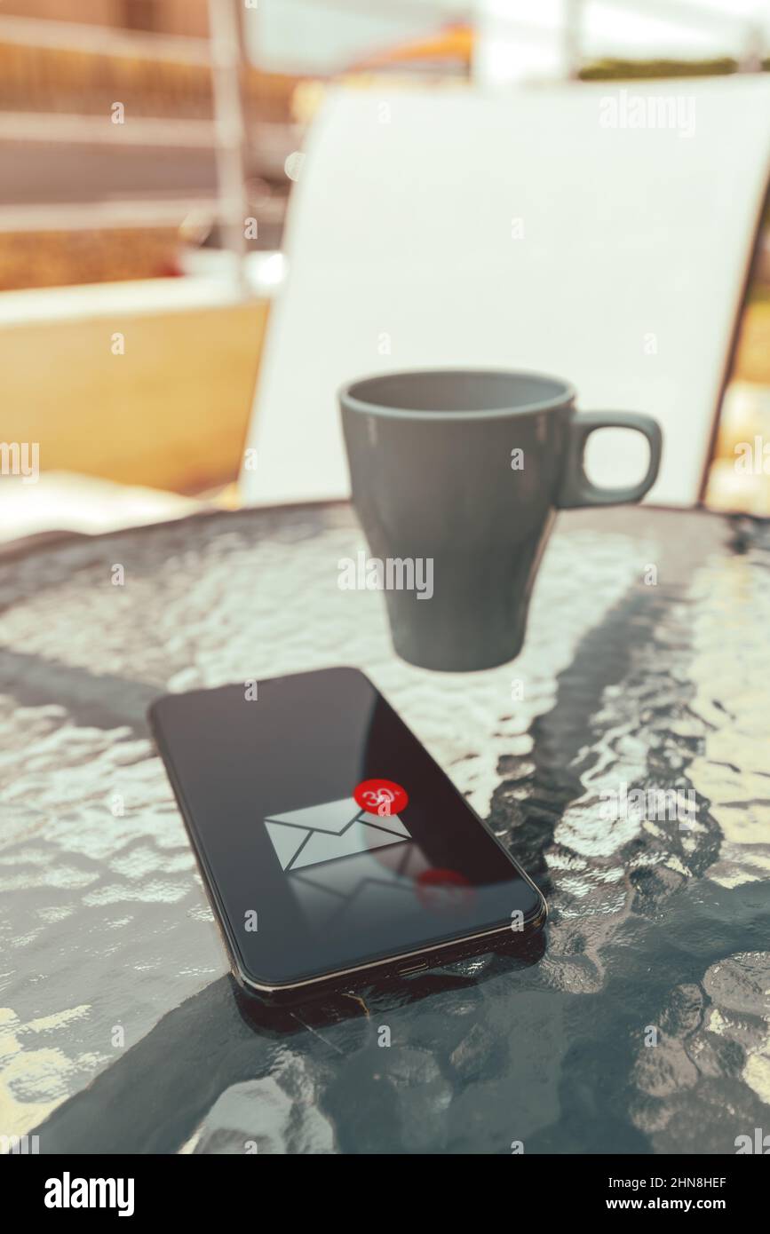 Messaggio di testo ricevuto su smartphone mobile sulla terrazza di casa in estate mattina, fuoco selettivo Foto Stock