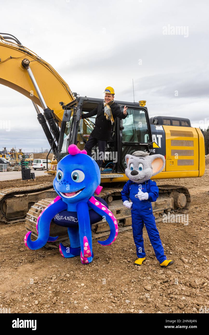 Ruggine, Germania. 14th Feb 2022. Stefan Mross, trombettista, cantante e presentatore, si erge su un escavatore presso il cantiere della nuova arena per lo spettacolo 'Immer wieder Sonntags', mentre di fronte si trovano le mascotte Snorri del parco acquatico Rulantica e la mascotte 'Euro-Maus' di Europa-Park. Europa-Park ha demolito la vecchia arena della trasmissione 'Immer wieder Sonntags' per la costruzione di una nuova montagne russe e sta costruendo una nuova e più grande arena altrove. La prima trasmissione è prevista per il 12 giugno 2022. Credit: Rin/dpa/Alamy Live News Foto Stock