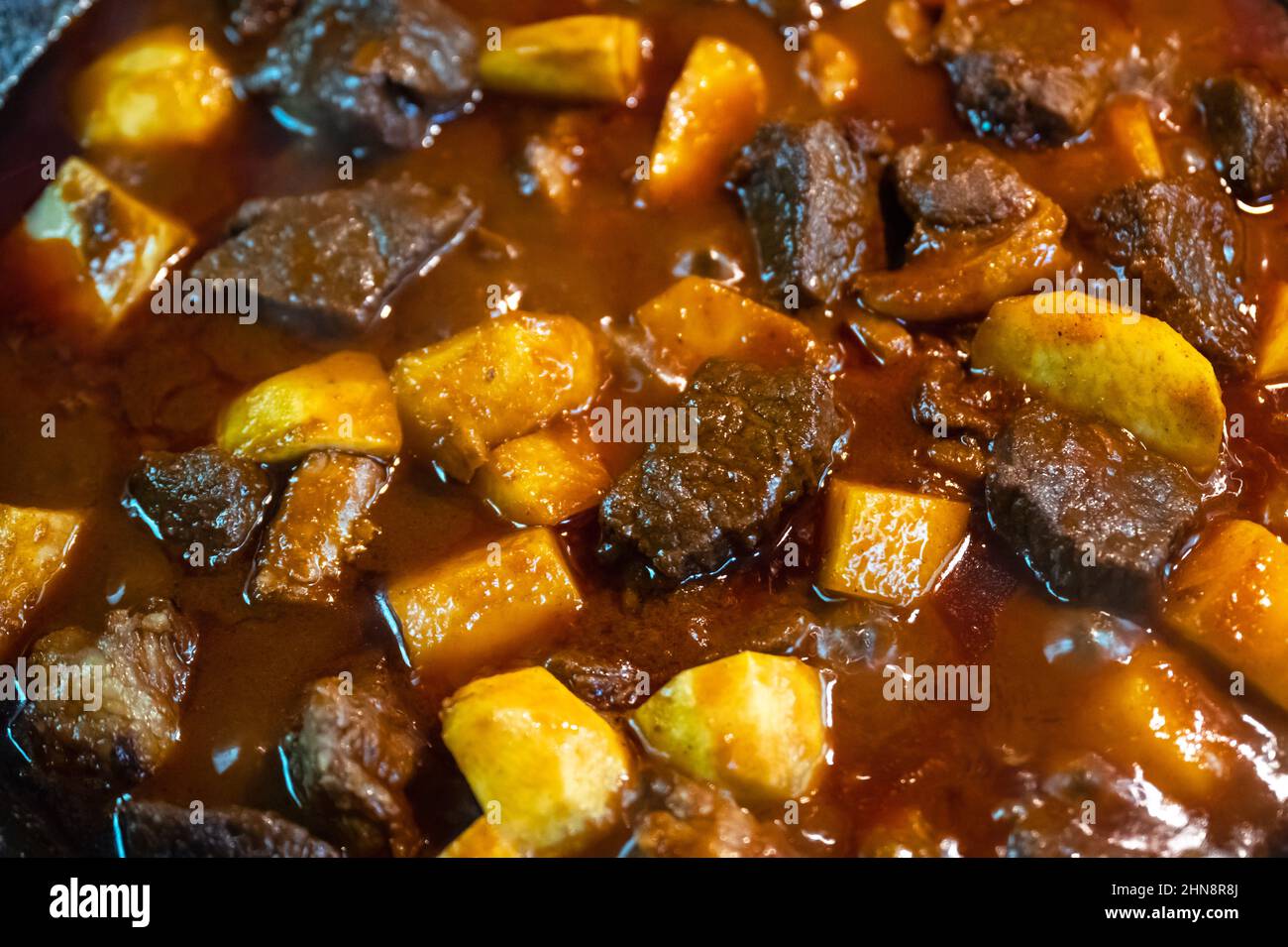 Cottura del goulash con manzo, patate, pomodoro e paprika in padella profonda nella cucina di casa. Fotografia alimentare Foto Stock