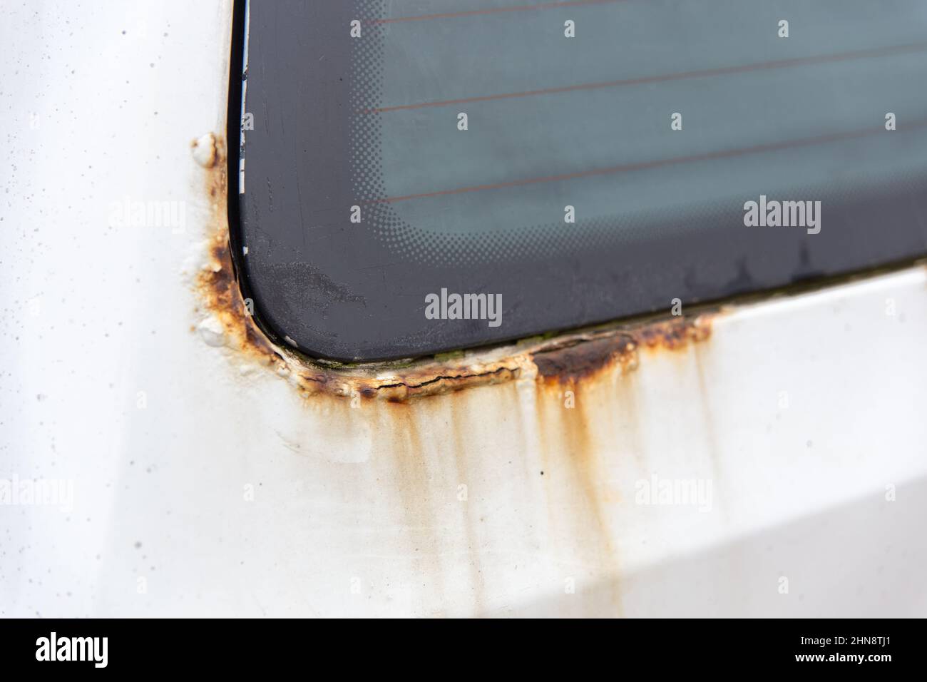 Ruggine sul lato della vecchia auto bianca. Foro di ruggine sulla vecchia superficie metallica verniciata usurata. Foto Stock