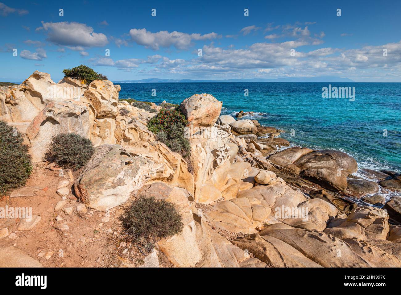 Vista della pittoresca scena di onde di mare che si infrangono sulle rocce di un'isola panoramica vicino alla città di villeggiatura nella regione di Halkidiki Foto Stock