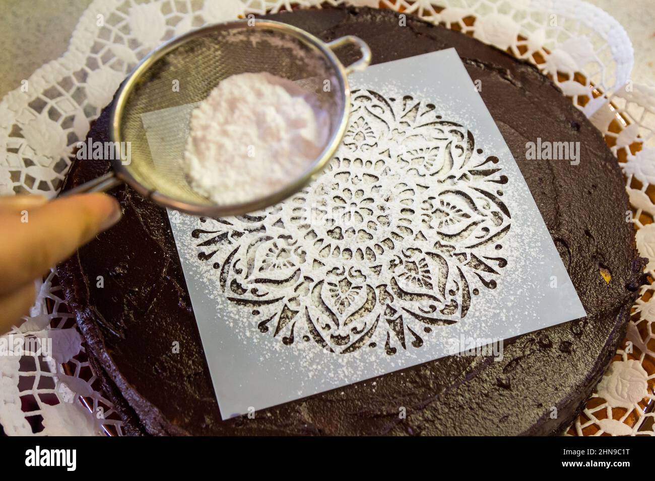 Stencil riutilizzabile per la glassa sulla torta al cioccolato, cosparso di dolcificante sostitutivo dello zucchero Foto Stock