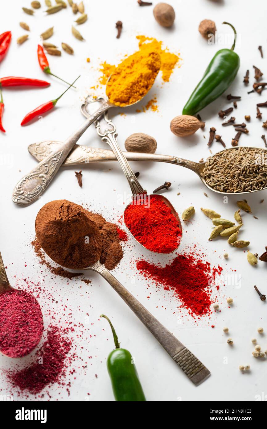 Primo piano di cannella, curry e paprika in polvere spezia su cucchiai di anice di cumino bianco superficie Foto Stock