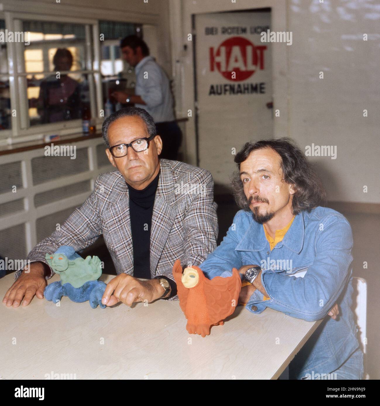 Regisseur Peter Loos (Links) und Maler, Sänger und Dichter Arik Brauer sitzen an einem Tisch, darauf eine rote Eule, Deutschland um 1974. Foto Stock