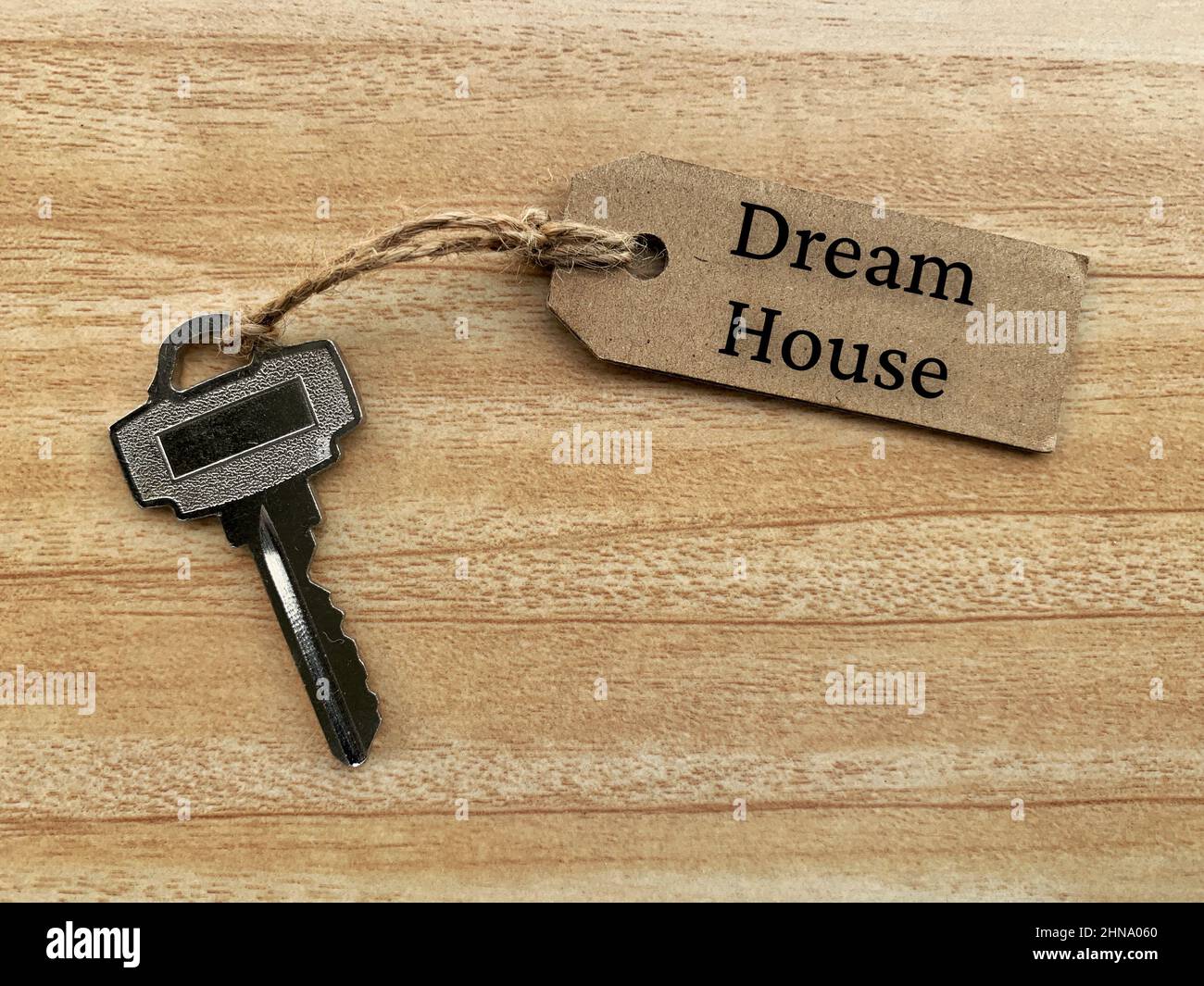 Testo su etichetta marrone con chiave casa e sfondo tavola in legno - Dream House. Concetto di proprietà. Foto Stock