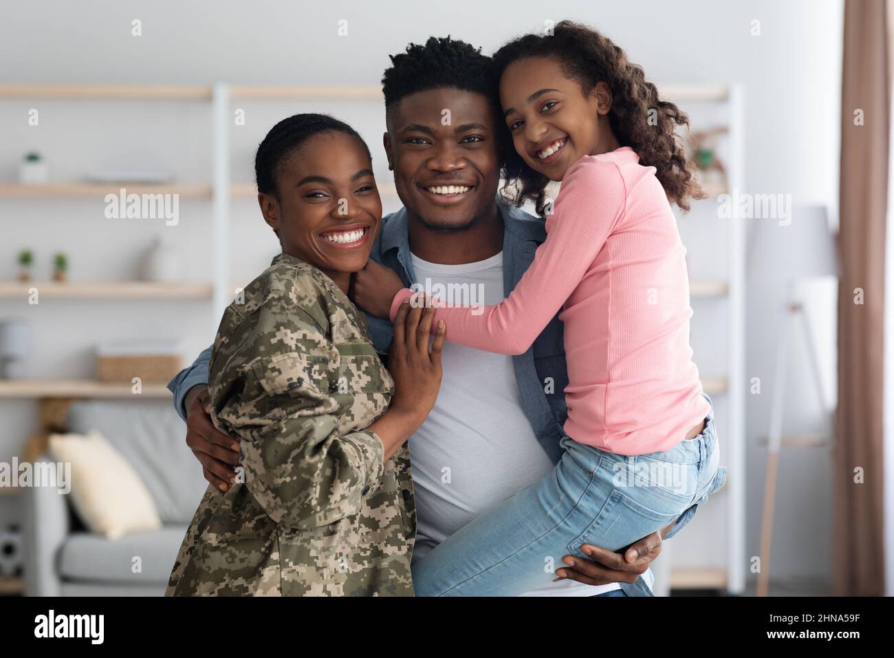Donna in uniforme militare con la sua famiglia a casa Foto Stock