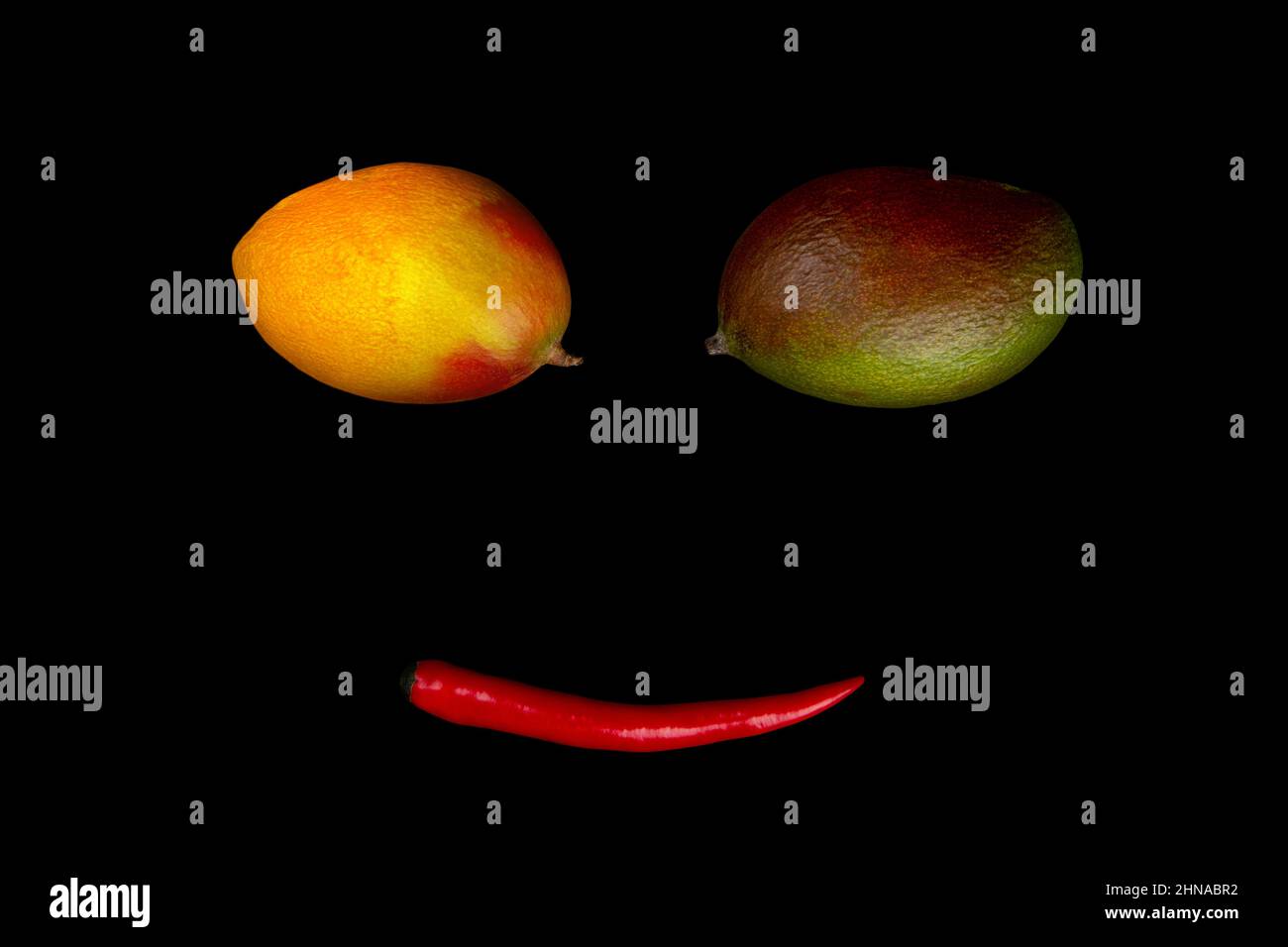 Faccia divertente di mango e peperoncino isolato su sfondo nero Foto Stock