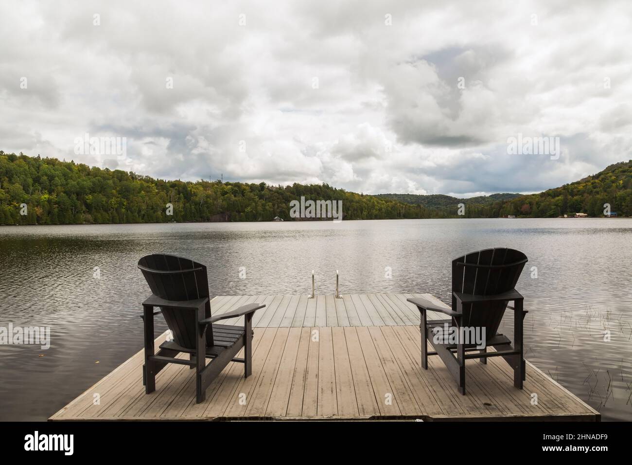Molo galleggiante con due sedie Adirondack con vista lago in estate. Foto Stock