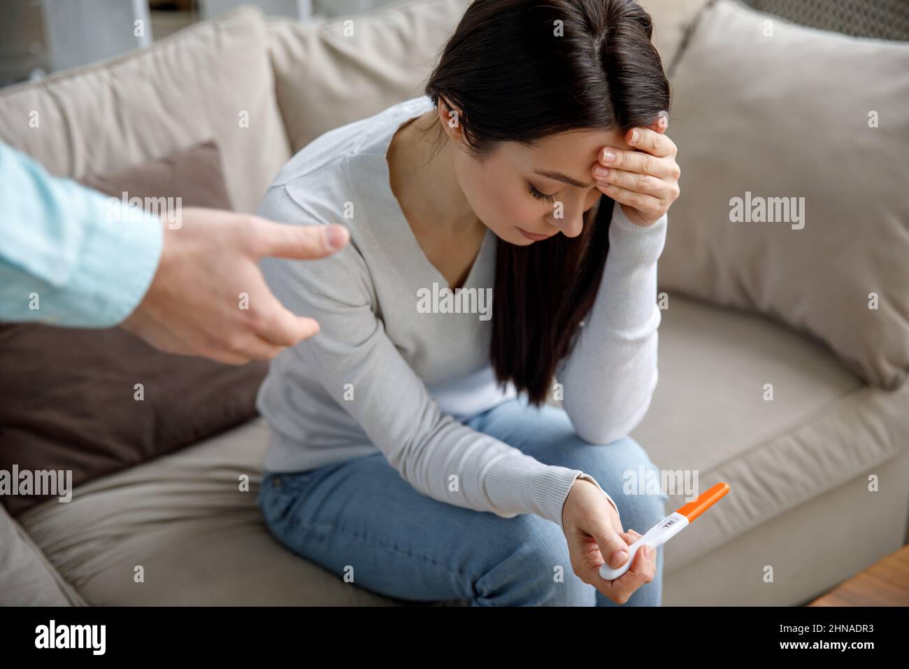 Una giovane donna triste tiene in mano un test di gravidanza. Il concetto di gravidanza indesiderata. Foto Stock