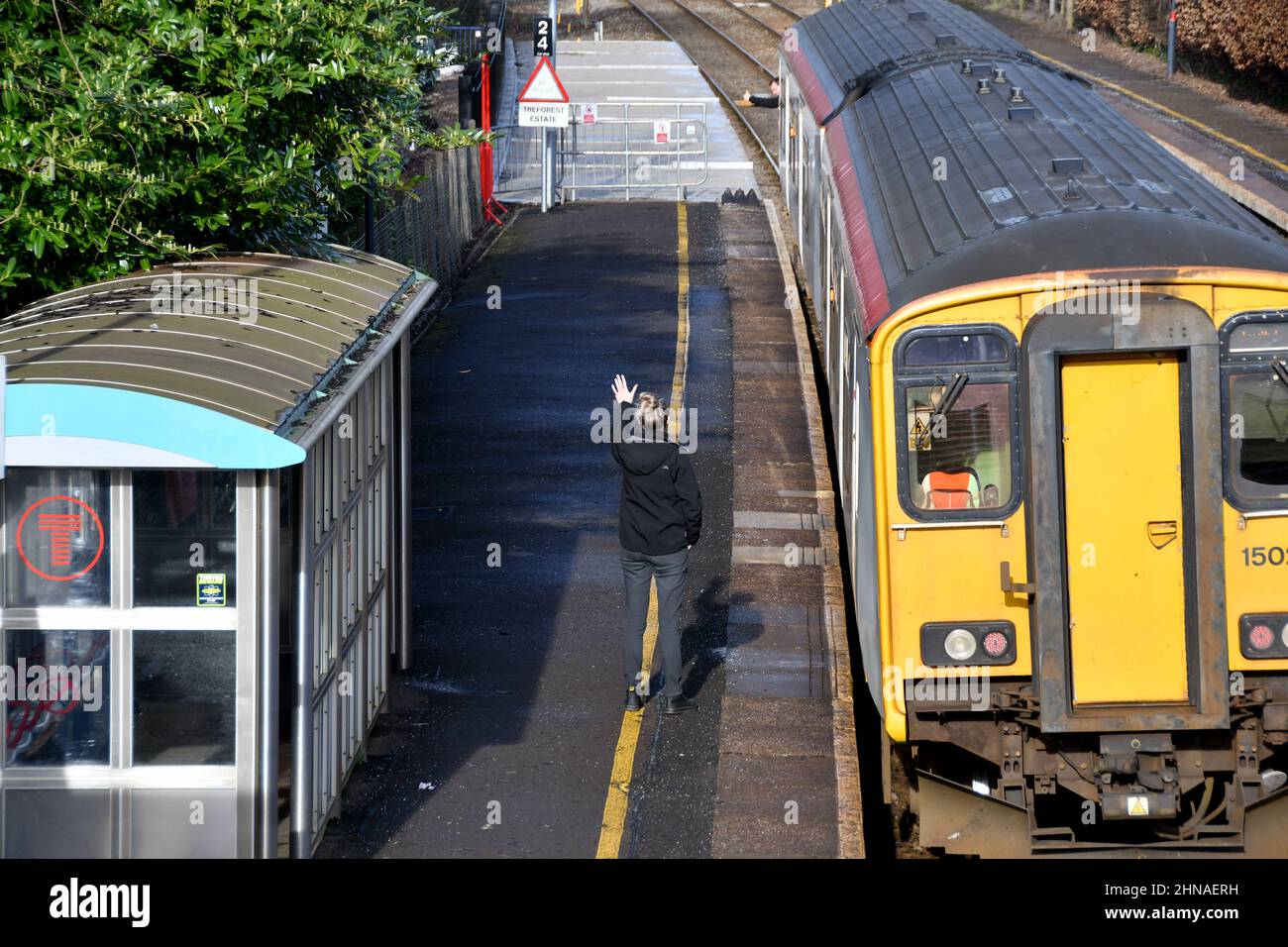 Taffs Well, Galles - Febbraio 2022: Guardia ferroviaria e autista segnalarsi a vicenda come un treno sta per lasciare la stazione ferroviaria a Taffs Well Foto Stock