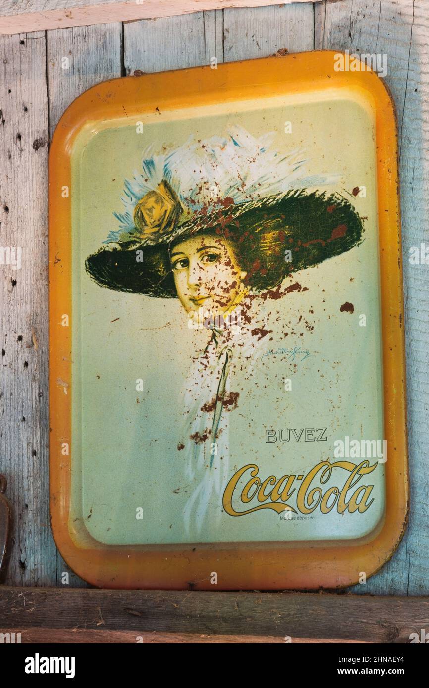 Vintage in francese Coca Cola vassoio in metallo con serigrafia ritratto donna su parete all'interno di una vecchia cabina rustica in legno. Foto Stock