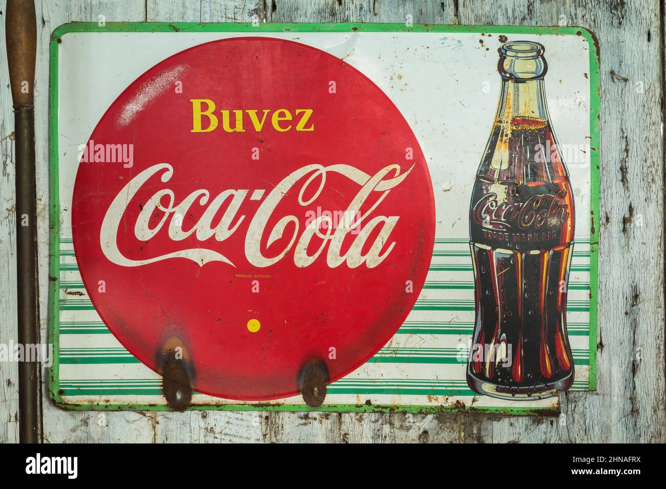 Vintage francese lingua Coca Cola metallo pubblicità segno sul muro all'interno di vecchio rustico legno tavola cabina. Foto Stock