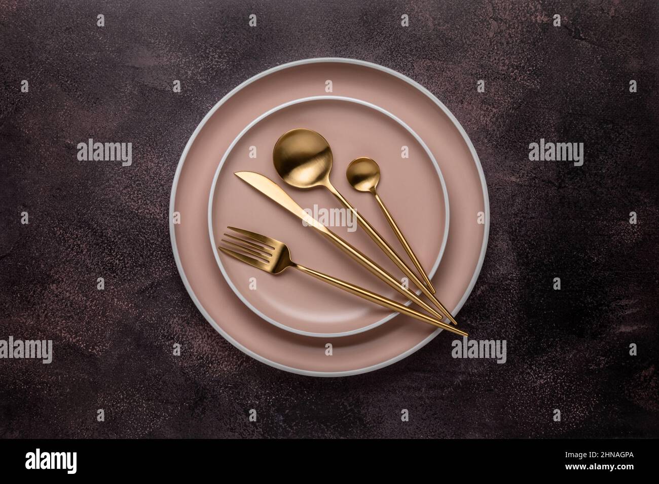 Collezione di piatti tondi beige su un vecchio tavolo marrone scuro, shabby board, vista dall'alto. Posate e stoviglie dorate per servire e mangiare. Artigianato moderno Foto Stock