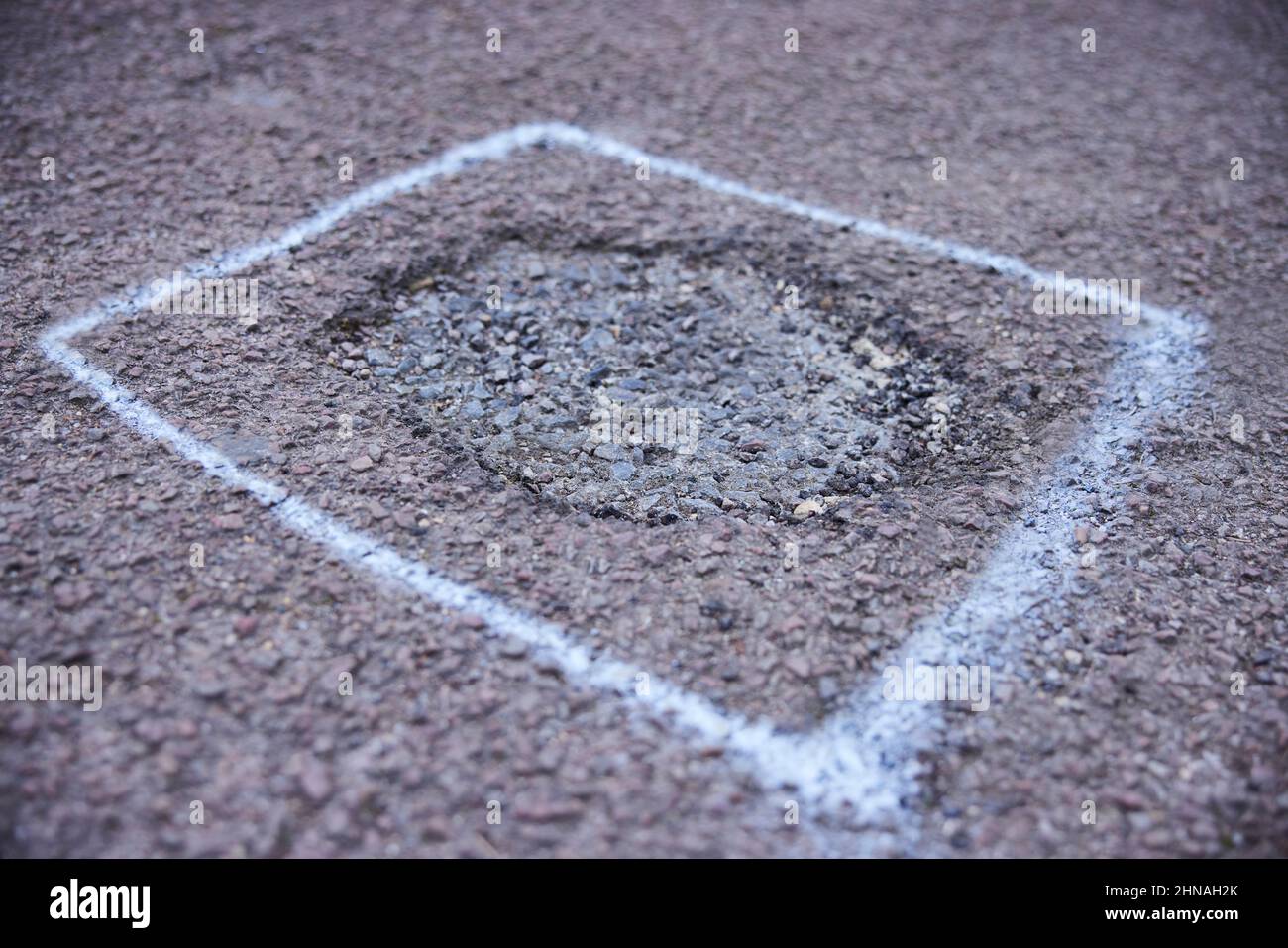 Primo piano di Pothole in Road contrassegnato per la riparazione Foto Stock