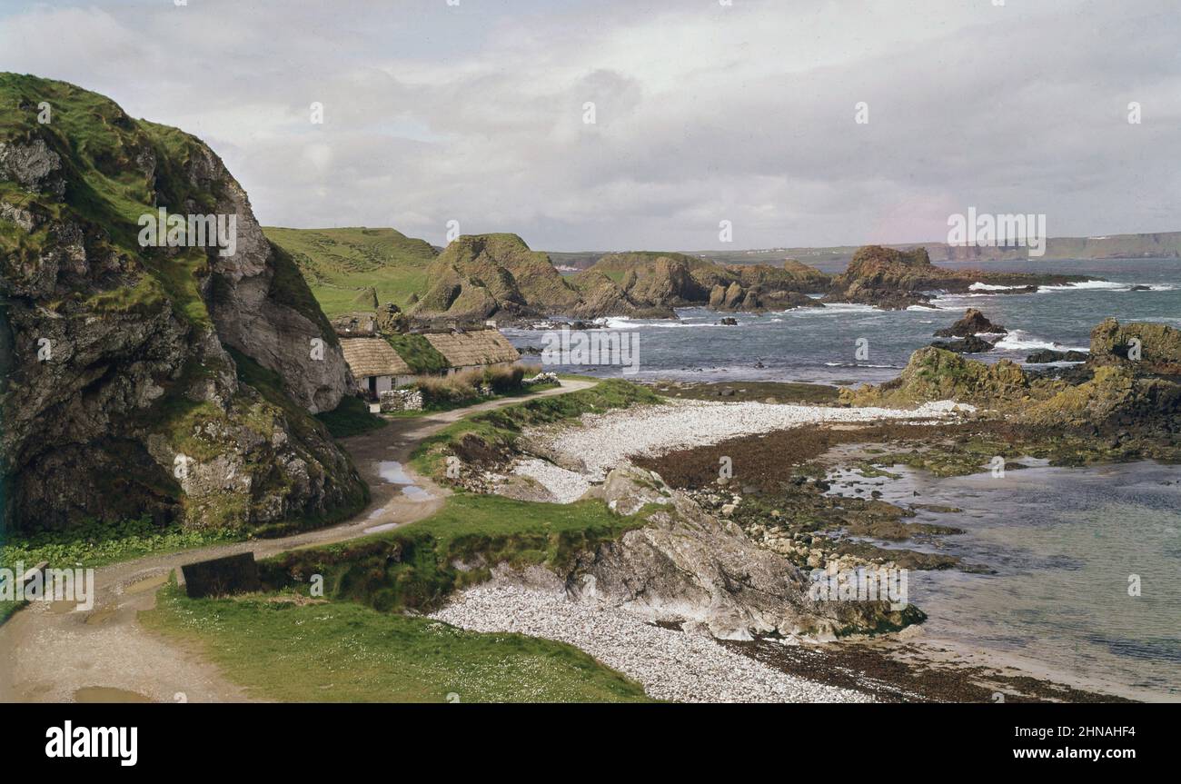 1960s, vista storica da questa epoca di attraverso la pittoresca baia a Ballintoy, Co Antrim, Irlanda del Nord, Regno Unito, che mostra piccole spiagge di ghiaia e costa frastagliata. Più recentemente è stata la location per la serie TV Game of Thrones. Foto Stock