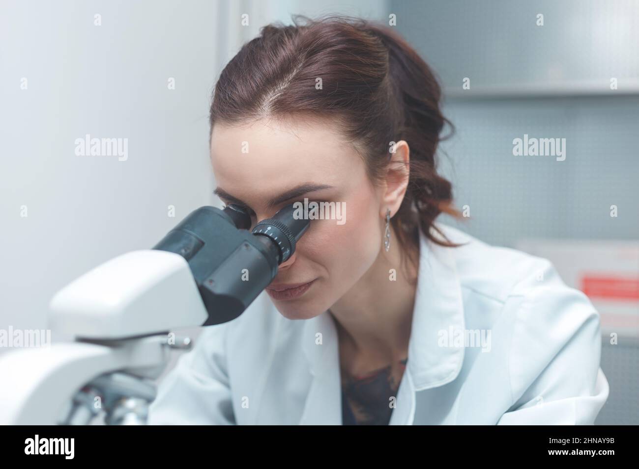 Donna scienziata che ricerca al microscopio in laboratorio Foto Stock