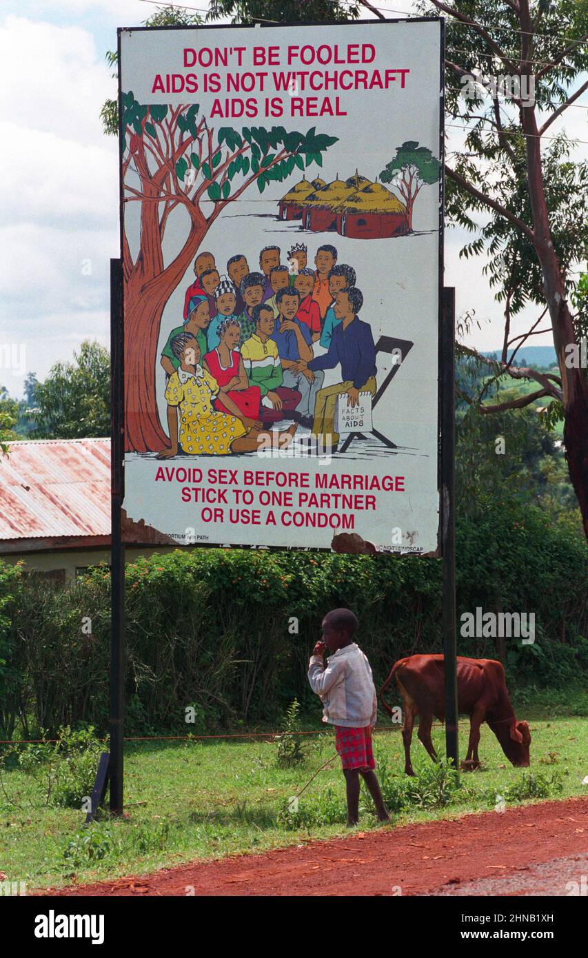Ragazzo che branda mucca con il segnale di avvertimento di AIDS, Tanzania Foto Stock