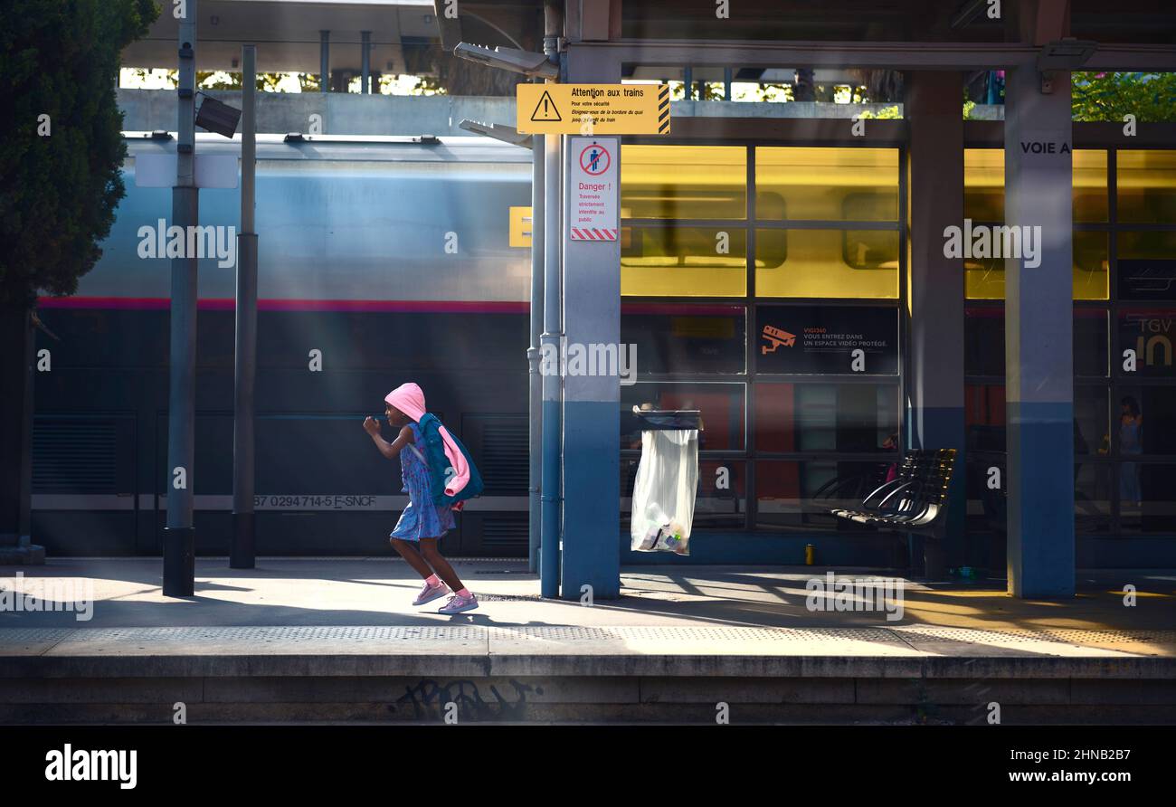 Una giovane ragazza eccitata corre lungo una piattaforma di stazione. Cannes, Francia Foto Stock