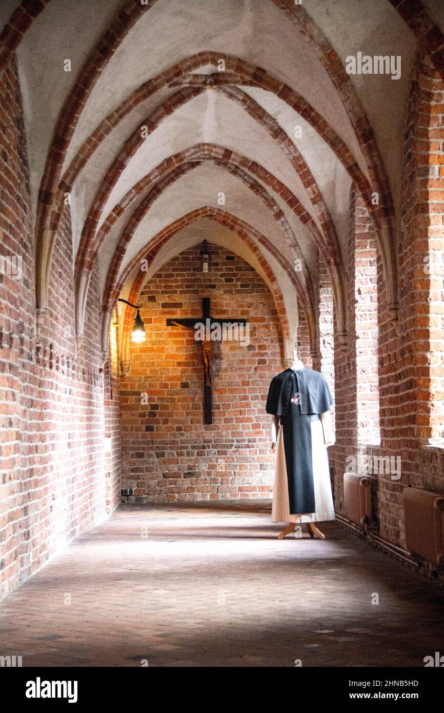 Colpo verticale di un corridoio in un monastero con un abito da suora e una croce sullo sfondo Foto Stock