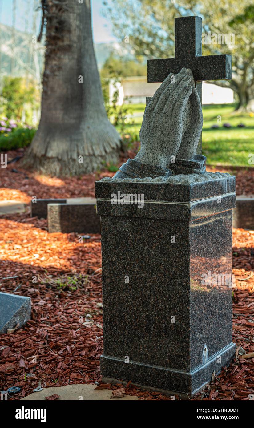 Santa Barbara, California, USA - 8 febbraio 2022: Cimitero di Calvario. Primo piano della statua di marmo nero che mostra palme pressate insieme in preghiera silenziosa dentro Foto Stock