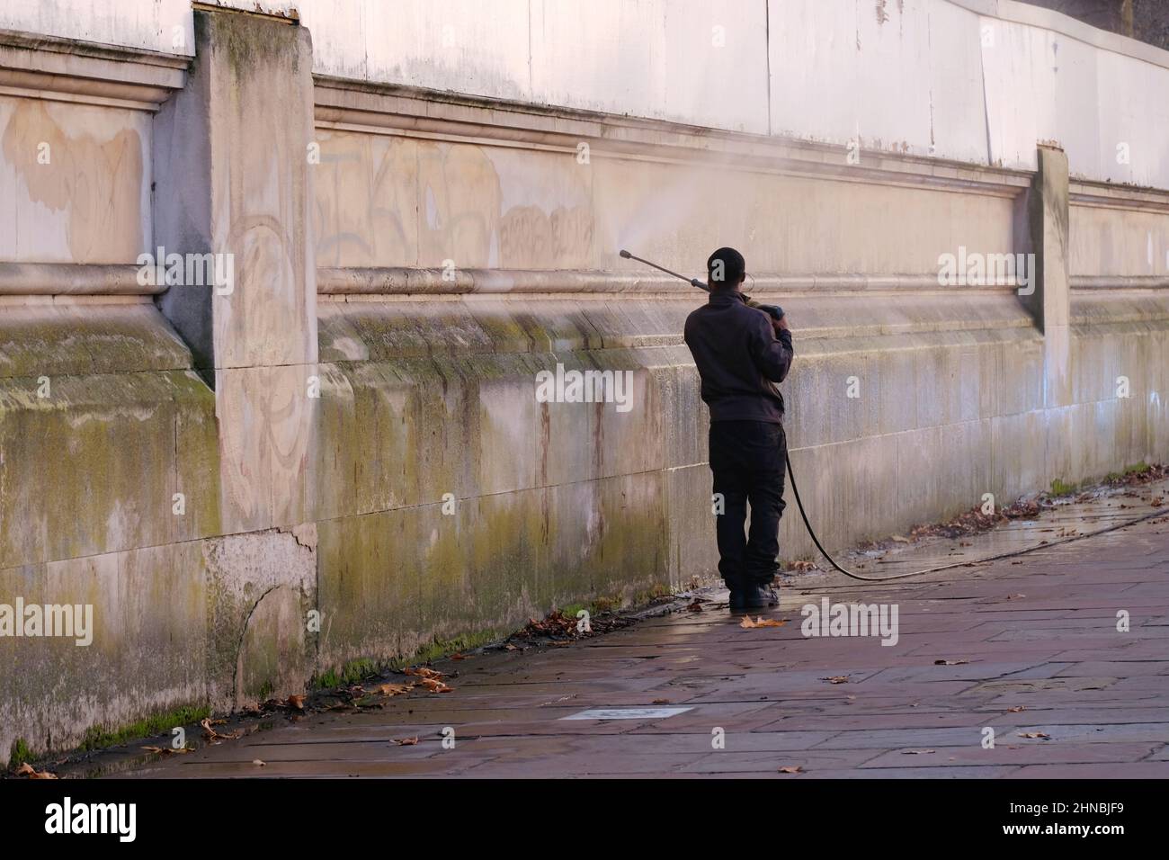 Londra, Regno Unito Un uomo pulisce il masonary con uno spruzzo del getto, rimuovendo le alghe ed i depositi dalla superficie Foto Stock