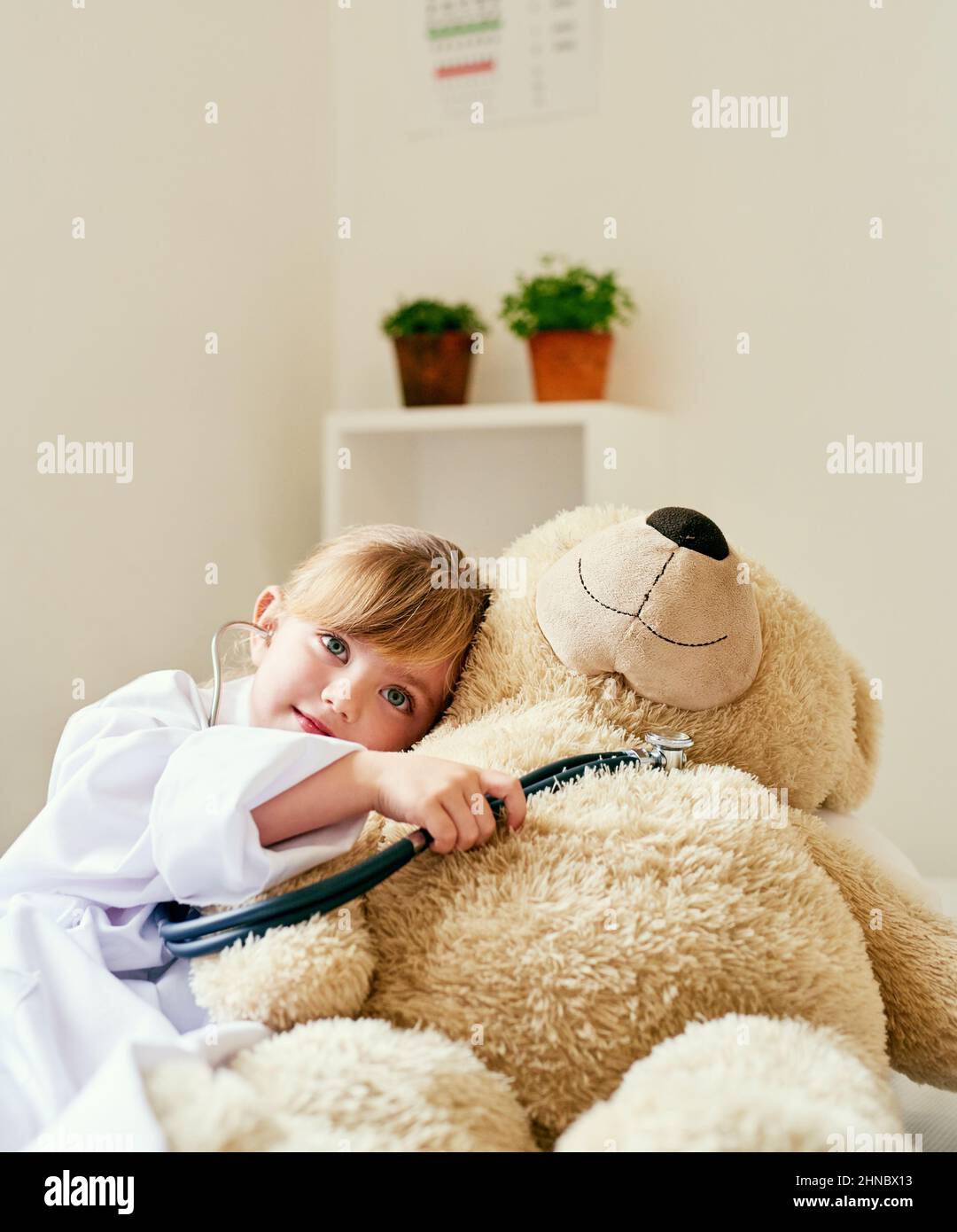 Imparare circa l'importanza della salute del cuore con il teddy. Shot di una bambina adorabile vestita come medico e l'esame di un orsacchiotto con un Foto Stock