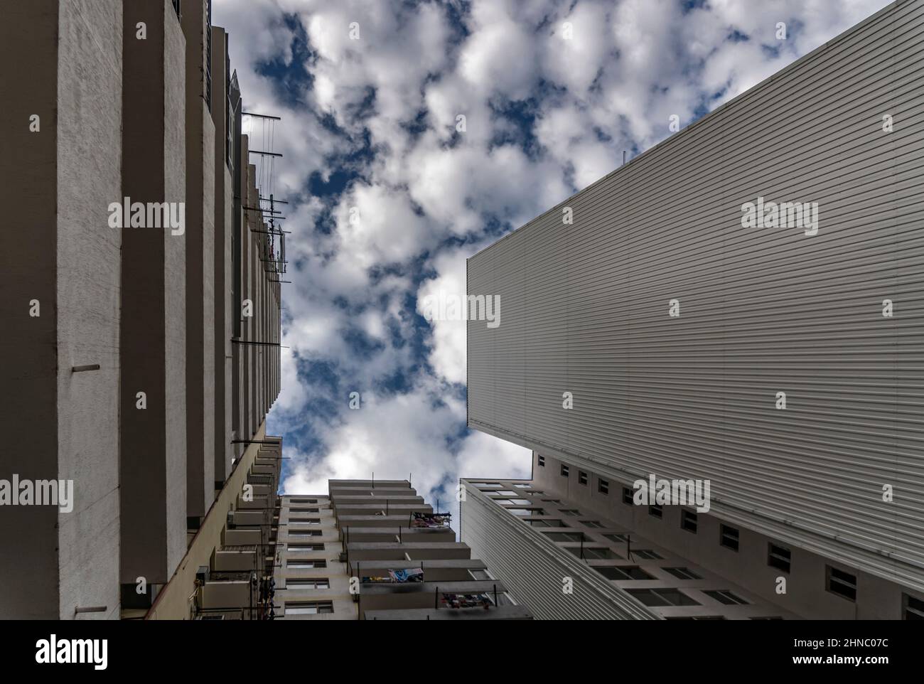 Cielo blu con nuvole bianche e morbide nel divario tra le torri di alti edifici. Biancheria secca sui balconi. Foto Stock
