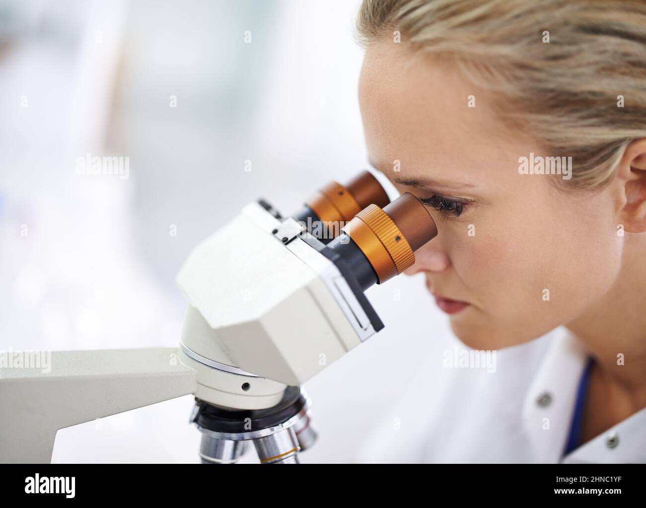 Scopri un mondo nuovo di zecca. Scatto di una bella donna in un laboratorio che lavora con un microscopio. Foto Stock