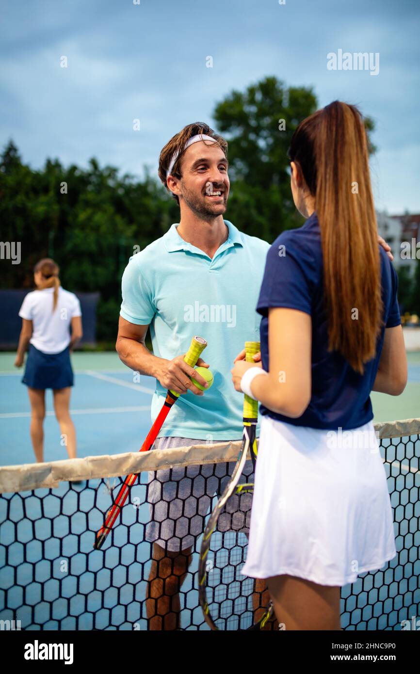 I giovani più belli giocano a tennis in squadra sul campo da tennis all'aperto. Concetto di sport delle persone Foto Stock