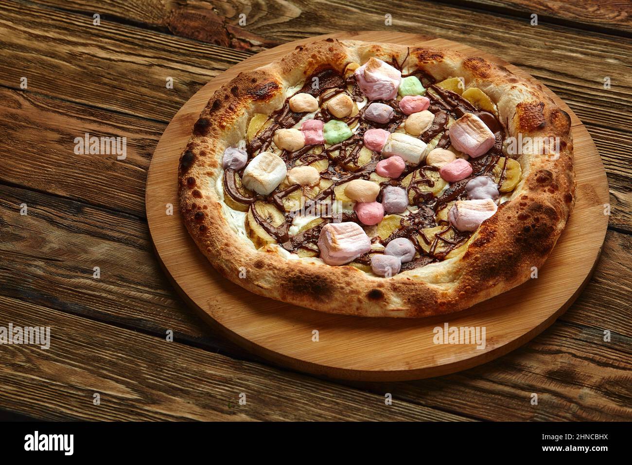 Pizza dolce intera servita con marshmallows e caramelle su sfondo di legno Foto Stock