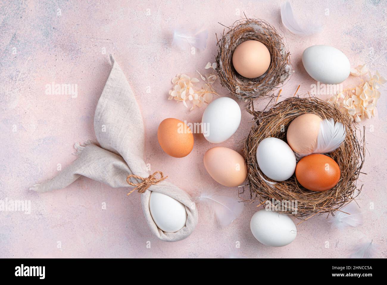 Coniglietto pasquale fatto di tovaglioli e uova in un nido su uno sfondo rosa chiaro. Il concetto di Buona Pasqua. Vista dall'alto. Foto Stock