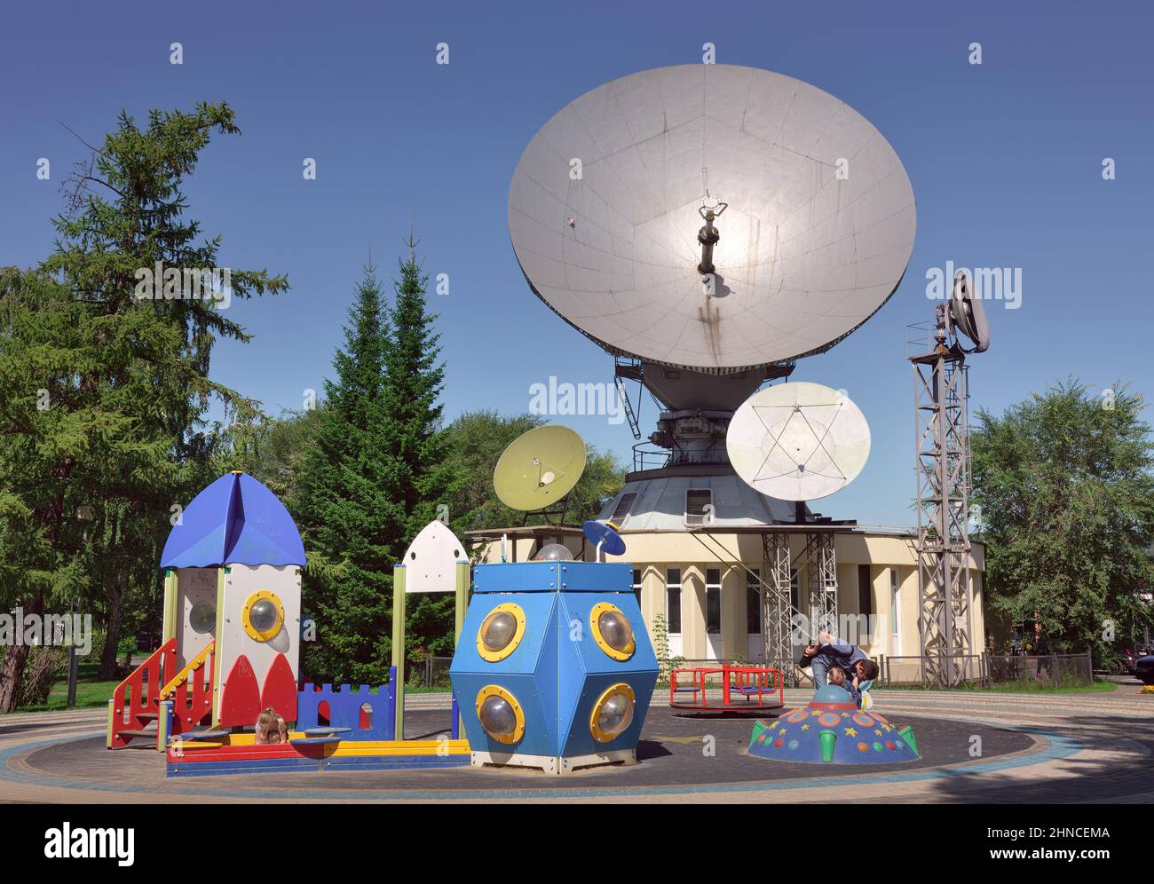 Kemerovo, Siberia, Russia -09.01.2021: Parco giochi sullo sfondo di un'antenna parabolica nel centro della città sotto un cielo blu Foto Stock