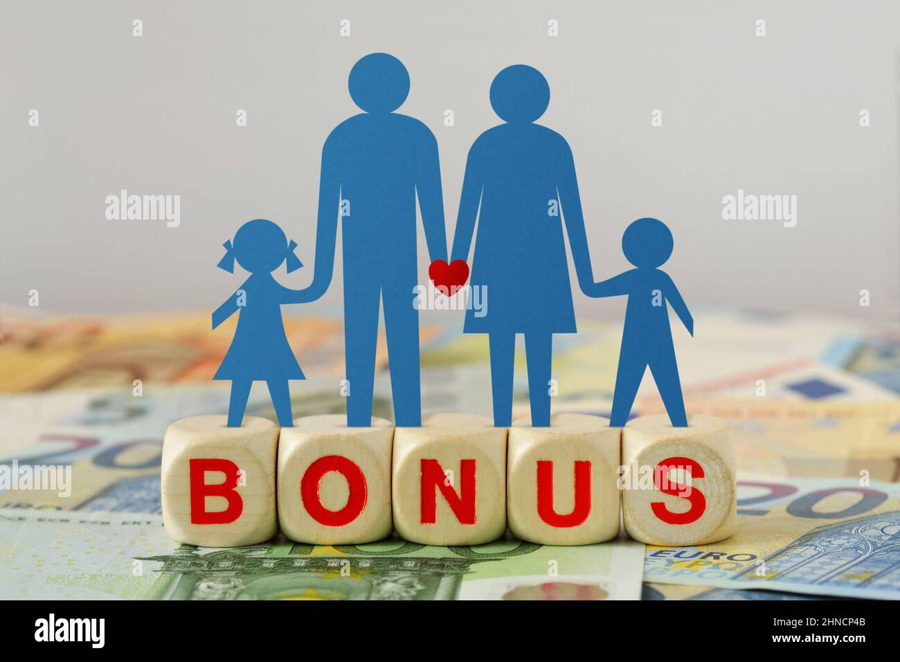 Carta silhouette di famiglia su blocchi di legno con la parola Bonus sulle banconote in euro - concetto di bonus economico e aiuto finanziario Foto Stock