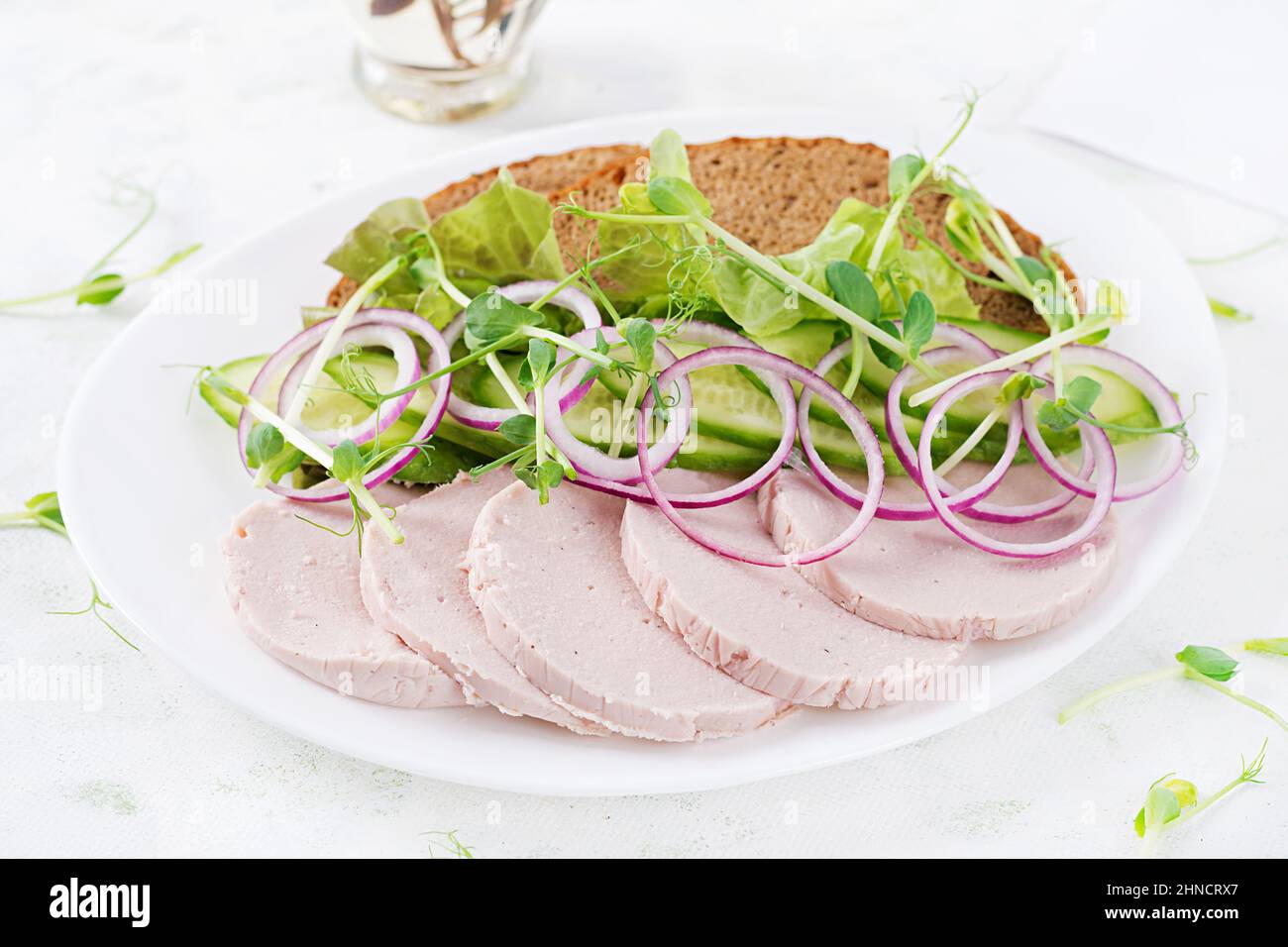 Sandwich con salsiccia di pollo fatta in casa, lattuga e cetriolo nel piatto Foto Stock