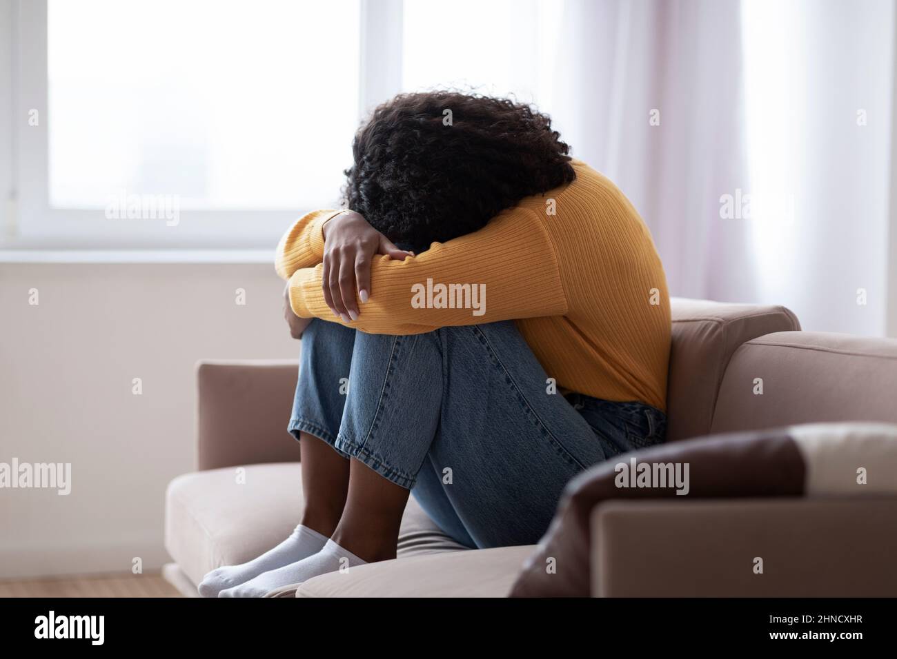 Giovane donna nera con depressione che piange sul divano a casa Foto Stock