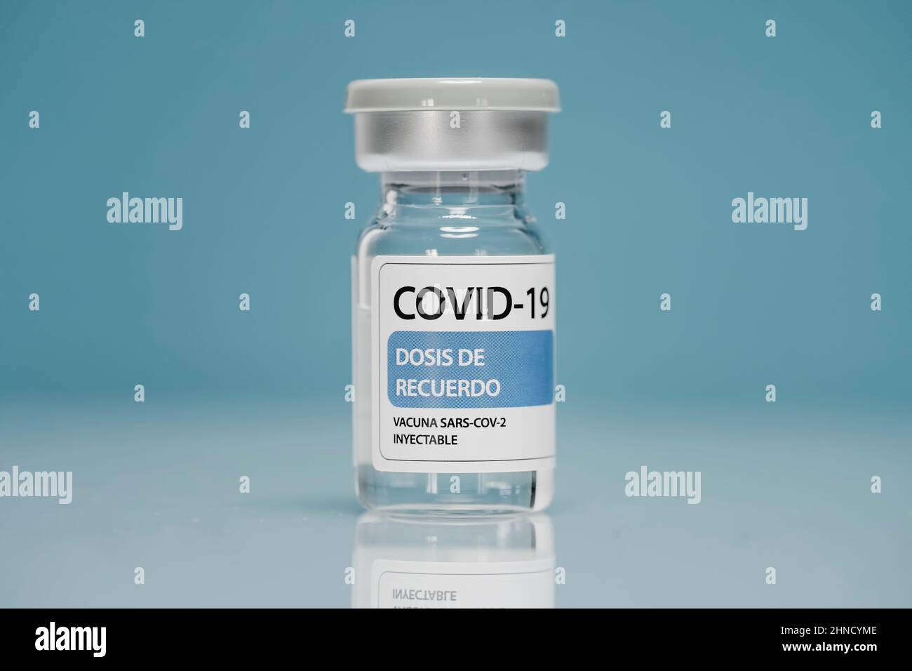 Flaconcino di vetro di richiamo medico con vaccino contro il coronavirus posto su sfondo blu Foto Stock