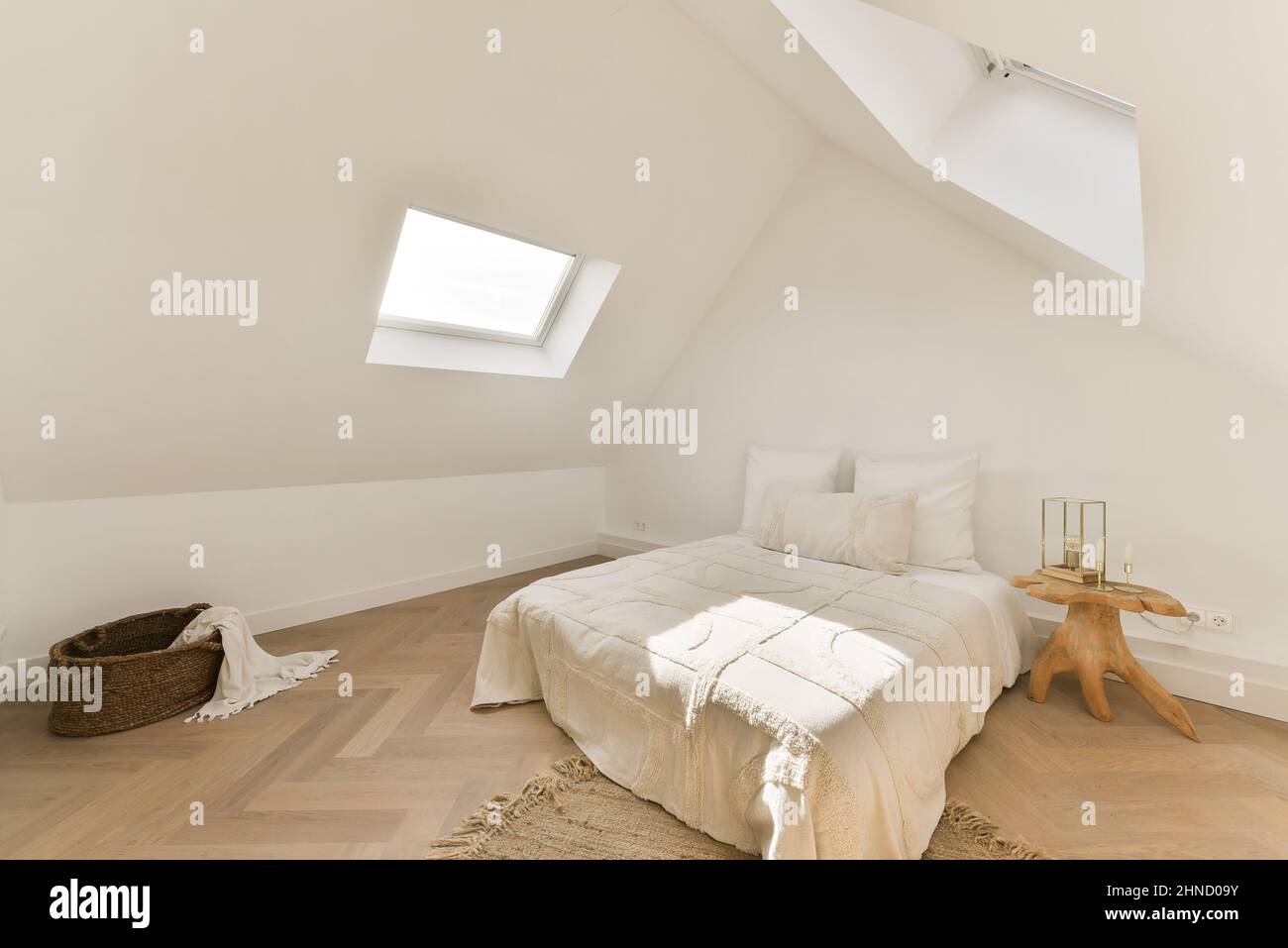 Interno della camera da letto in stile rustico con comodo letto con cuscini  e coperta vicino al comodino e cestino di vimini Foto stock - Alamy