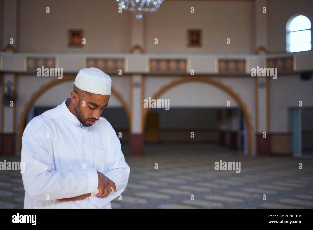 Un giovane musulmano in piedi durante le preghiere in una moschea Foto Stock