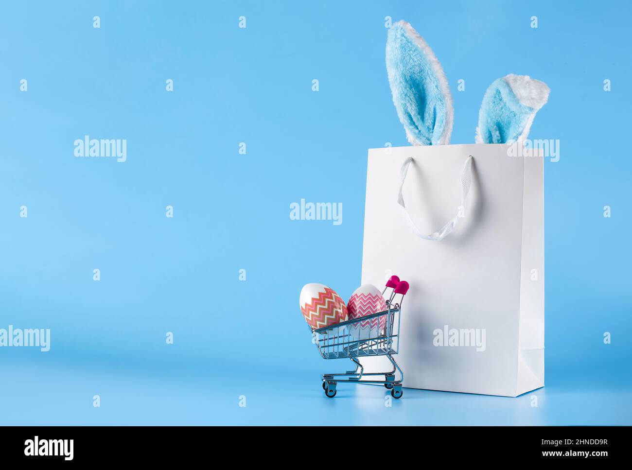 Banner di Pasqua, borsa regalo e carrello acquisti su sfondo blu. Foto Stock Banner di Pasqua, borsa regalo e carrello acquisti su sfondo blu. Foto Stock
