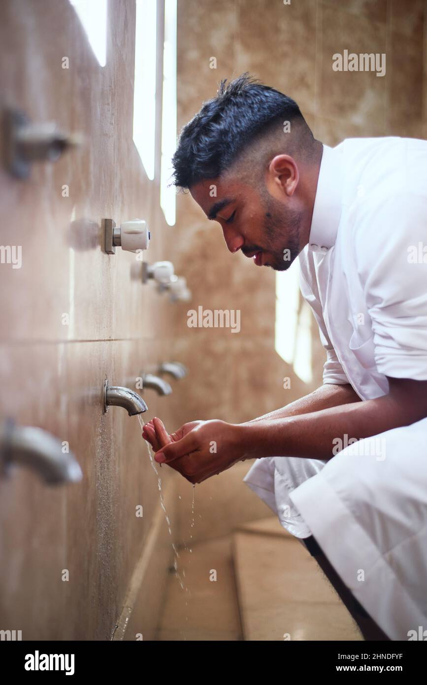 Un giovane musulmano pulisce le mani nel bagno Foto Stock