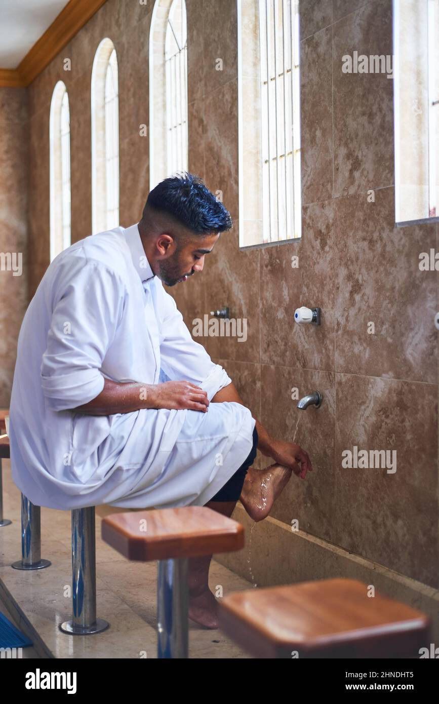 Un uomo musulmano che pulisce i piedi nel bagno della moschea Foto Stock