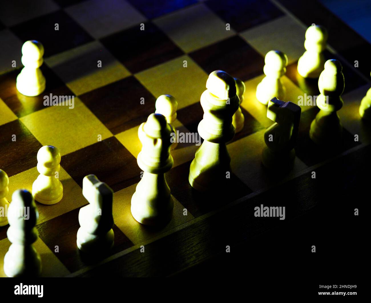 pezzi di scacchi drammaticamente illuminati su una tavola Foto Stock