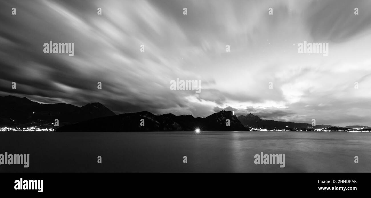 Astratto paesaggio notturno. Esposizione prolungata. Lago di Lucerna. Silhouette di montagna. Luci notturne sullo sfondo. Foto Stock