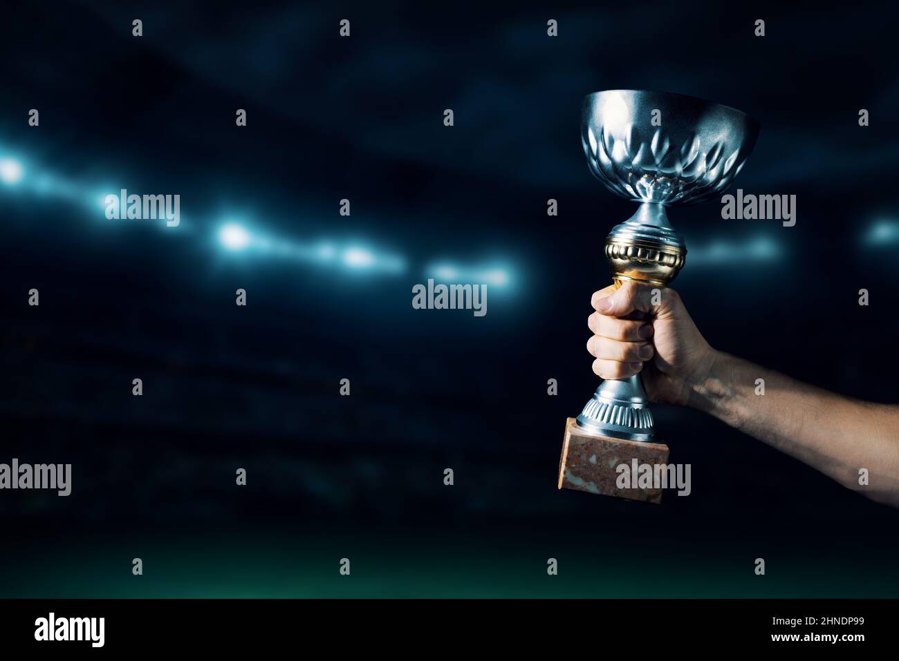 mano del vincitore che tiene in mano una coppa di trofei sullo sfondo dello stadio. spazio per le copie Foto Stock