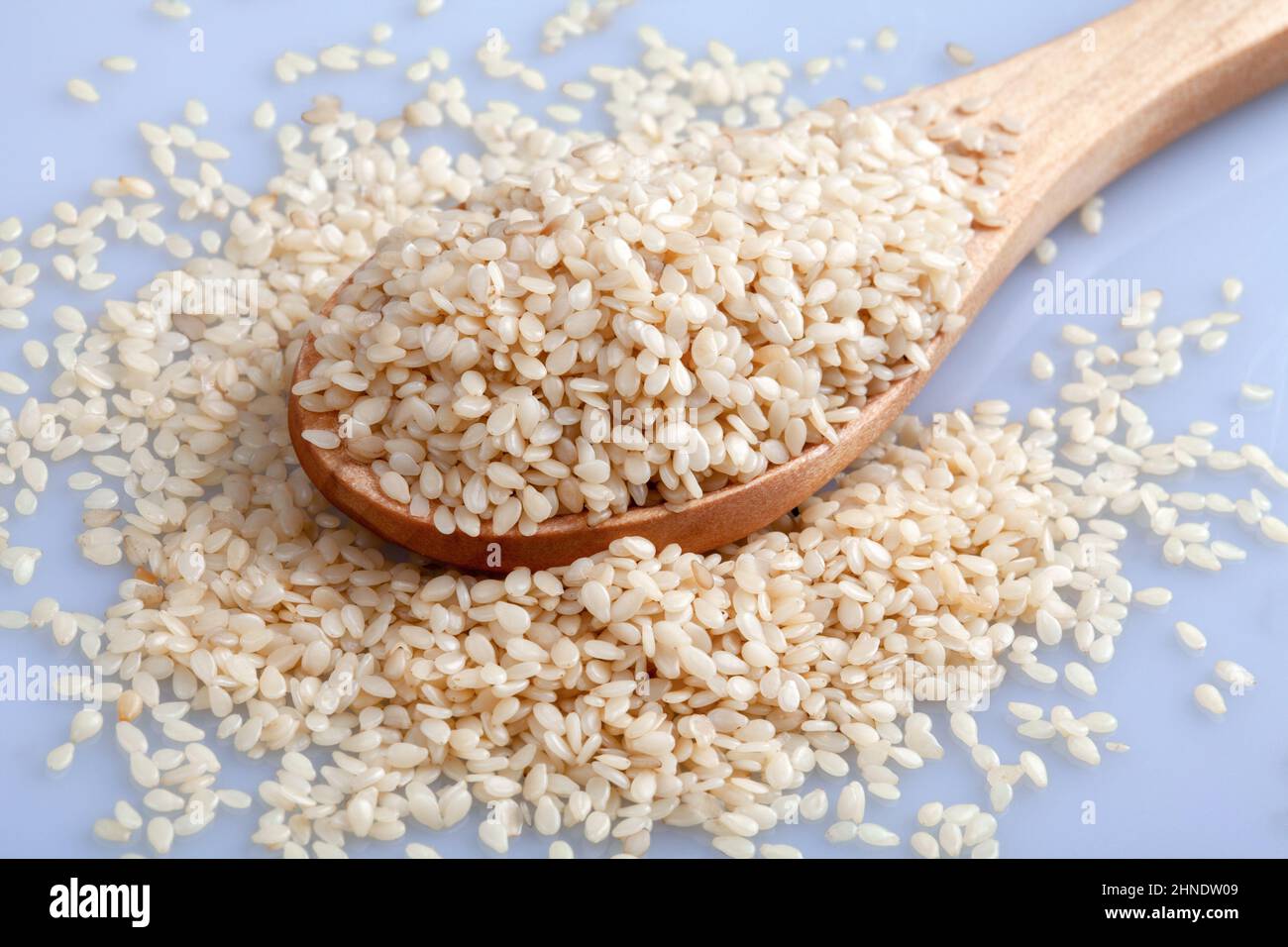 Cucchiaio di legno di semi di sesamo su sfondo bianco, vista dall'alto Foto Stock