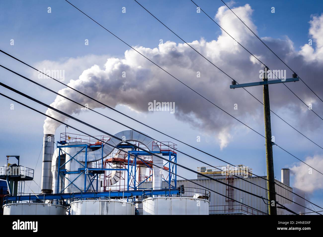 Una distilleria artigianale locale che emette vapore da una bocchetta di scarico con linee di trasmissione in primo piano a Calgary, Alberta, Canada. Foto Stock