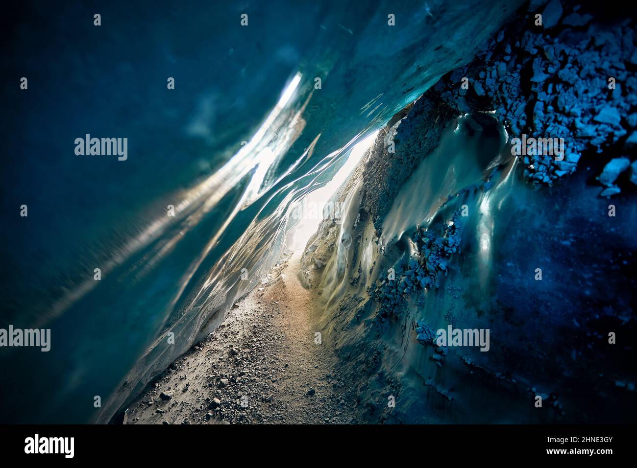 Paesaggio di incredibile grotta di ghiaccio glaciale con luci blu all'interno di una parete di ghiaccio nel profondo del ghiacciaio invernale di montagna in Kazakistan Foto Stock Paesaggio di incredibile grotta di ghiaccio glaciale con luci blu all'interno di una parete di ghiaccio nel profondo del ghiacciaio invernale di montagna in Kazakistan Foto Stock