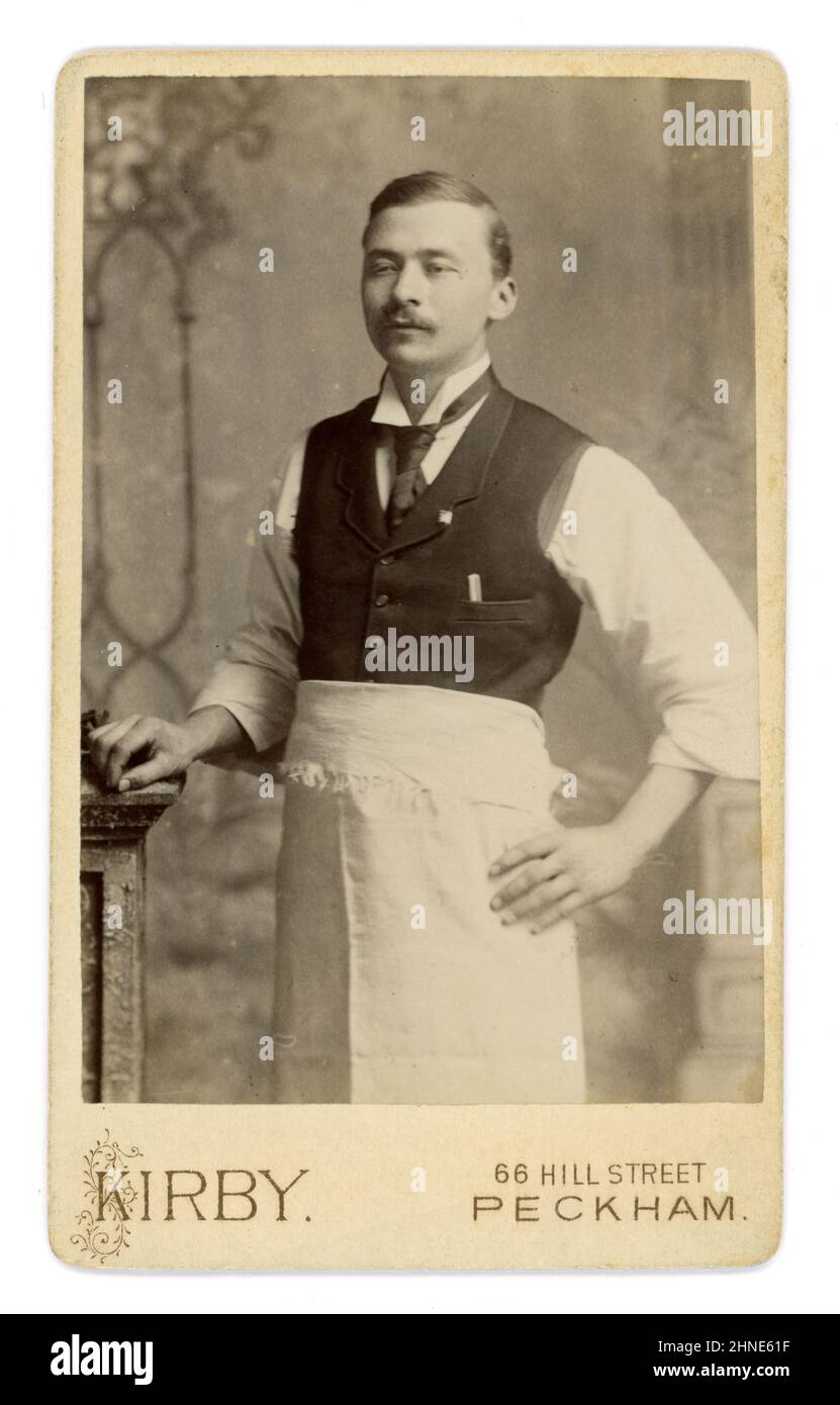 Originale Victorian carte de Visite (CDV) o biglietto da visita dell'uomo orientale che indossa un grembiule, colletto con punta ad alette, lappi stretti al gilet, bacchette in tasca, eventualmente un cameriere o un proprietario di un ristorante da Kirby's Studio 66 Hill Street, Peckham, Londra, Regno Unito circa alla fine del 1880s, 1890 Foto Stock