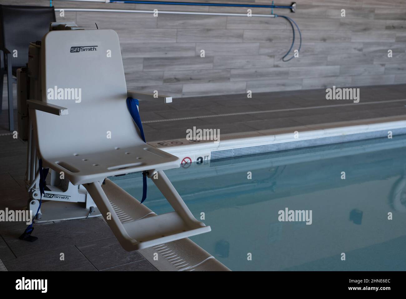 Ascensore per la piscina conforme ai requisiti ADA della SR Smith, situato ai margini di una piscina interna al coperto. Foto Stock